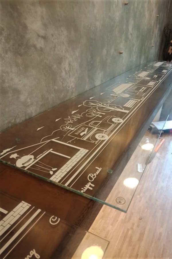 Graphical designs printed on a clear transparent vinyl using UV white inks. The film is then pasted on a glass shelf on enhance the looks of the same