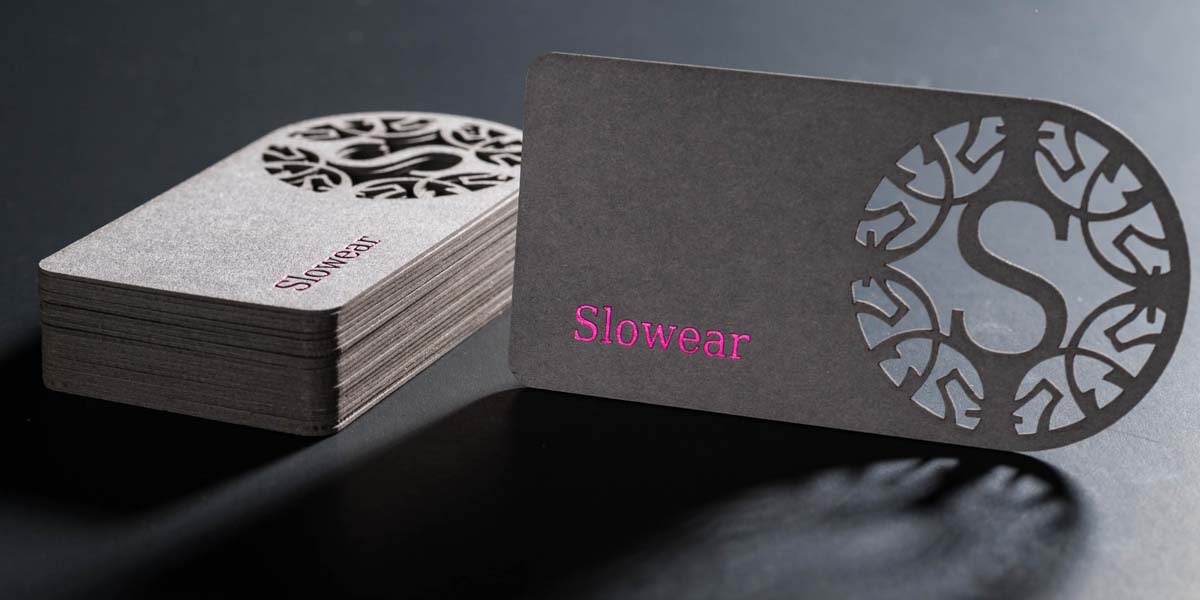 stack of laser cut business cards with a company logo cut through thick textured card paper
